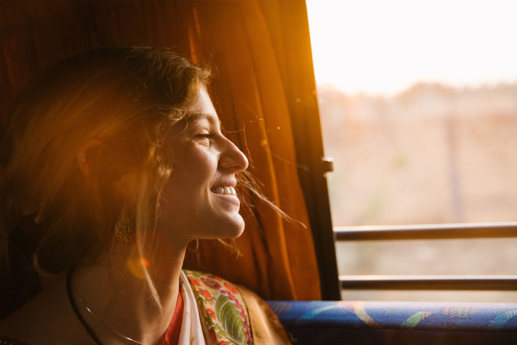 kvinna ler i solskenet som läggs på henne när hon åker buss